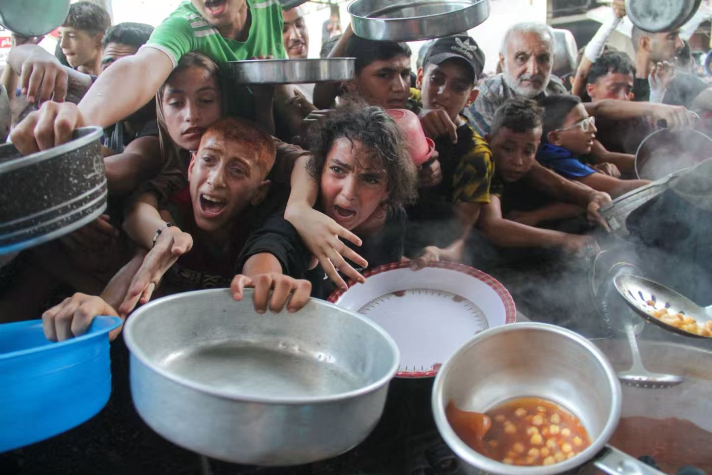 Crowds gather at a community kitchen as food is served